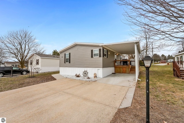 view of side of property with an attached carport, driveway, and a lawn