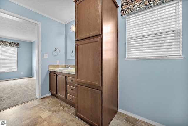 bathroom featuring a textured ceiling, vanity, baseboards, and ornamental molding