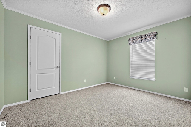 empty room with ornamental molding, baseboards, carpet, and a textured ceiling