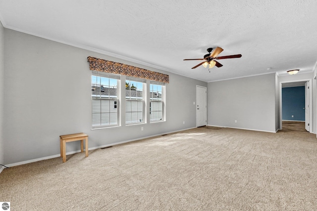spare room featuring crown molding, ceiling fan, carpet, a textured ceiling, and baseboards