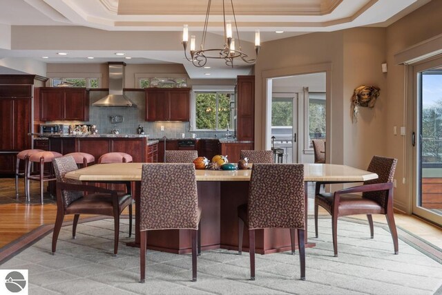6579 Woods Creek Dr, Charlevoix, MI 49720 - dining space with crown molding, a raised ceiling, an inviting chandelier, and light wood finished floors
