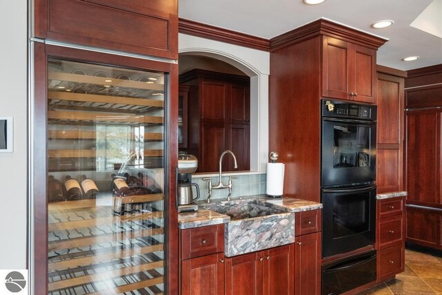 6579 Woods Creek Dr, Charlevoix, MI 49720 - kitchen with dobule oven black, arched walkways, a warming drawer, light stone counters, and backsplash