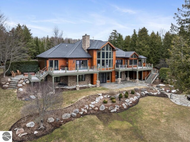 6579 Woods Creek Dr, Charlevoix, MI 49720 - back of house featuring a patio, a chimney, stairs, a yard, and a deck