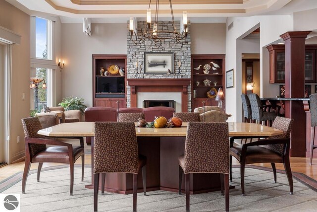 6579 Woods Creek Dr, Charlevoix, MI 49720 - dining area featuring an inviting chandelier, a tray ceiling, a large fireplace, visible vents, and a high ceiling
