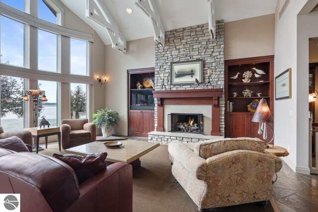 6579 Woods Creek Dr, Charlevoix, MI 49720 - living area with a towering ceiling, baseboards, a fireplace, stone finish floor, and beam ceiling