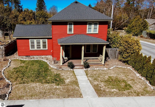 view of front facade featuring fence, a porch, a shingled roof, and a front yard