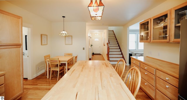 dining space with light wood-type flooring and stairway