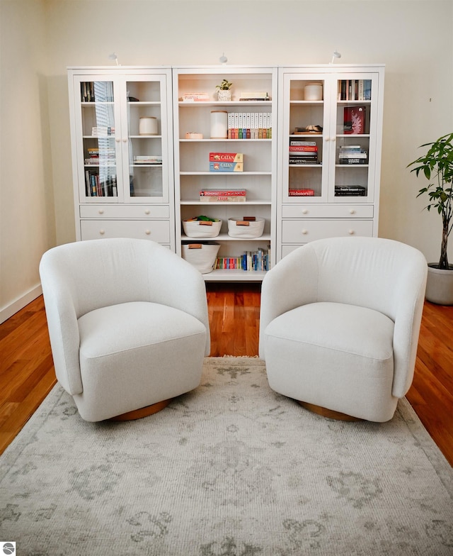 sitting room with baseboards and wood finished floors