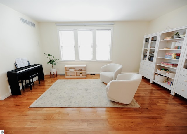 living area featuring light wood-type flooring, visible vents, and baseboards