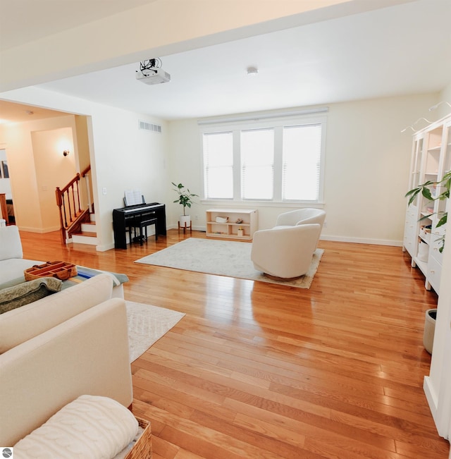 living room with stairway, visible vents, light wood finished floors, and baseboards