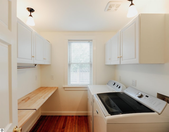 laundry room with dark wood finished floors, baseboards, visible vents, independent washer and dryer, and cabinet space