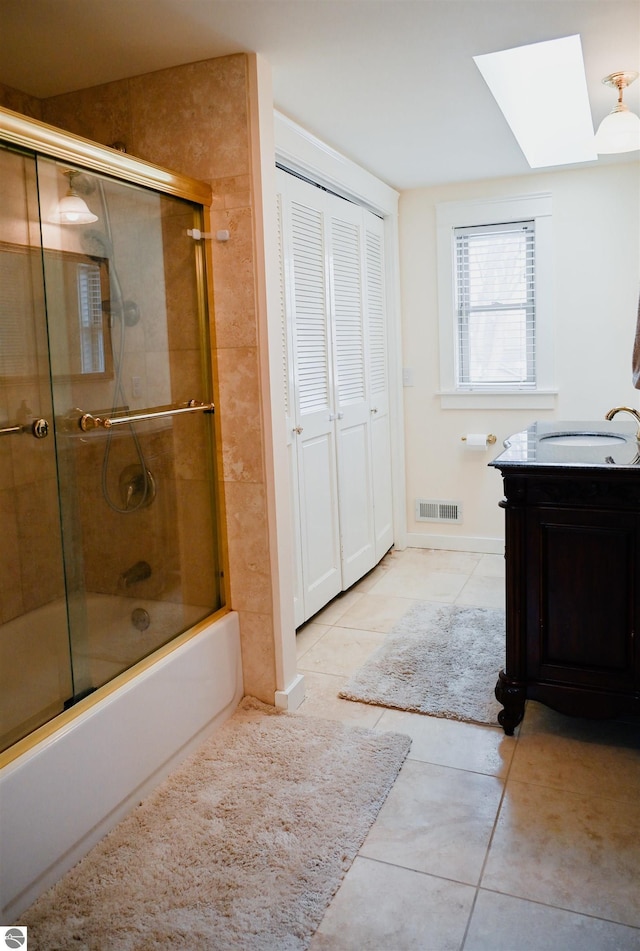 bathroom with a skylight, vanity, enclosed tub / shower combo, tile patterned flooring, and visible vents