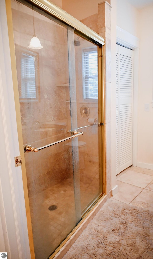bathroom with a shower stall, tile patterned floors, and baseboards