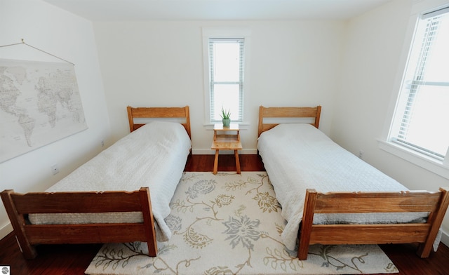 bedroom with baseboards, multiple windows, and wood finished floors