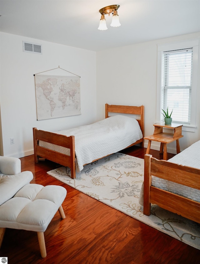 bedroom with baseboards, wood finished floors, and visible vents