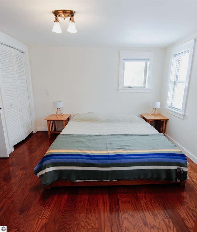 bedroom with baseboards, wood finished floors, and a closet