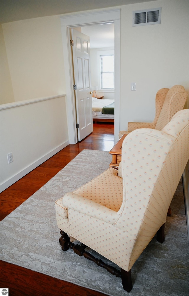 living area featuring baseboards, wood finished floors, and visible vents