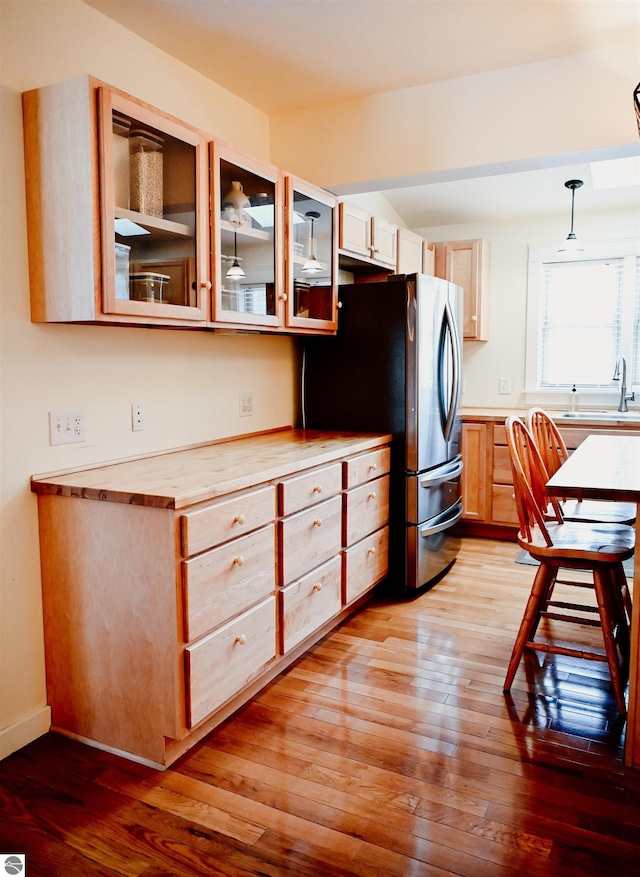kitchen with wood counters, light wood-style floors, glass insert cabinets, and freestanding refrigerator