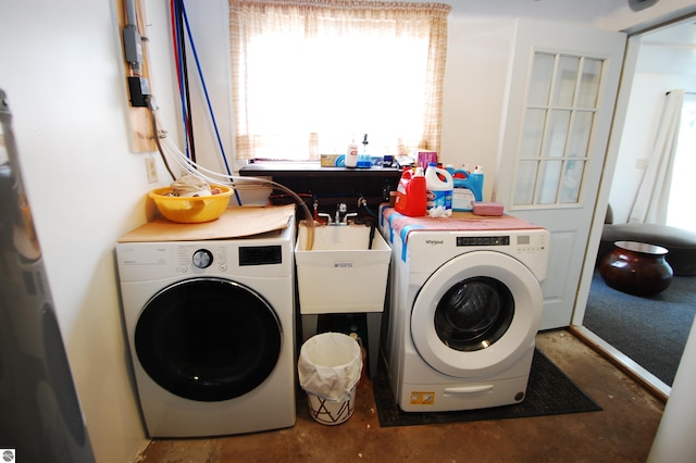 clothes washing area with washing machine and clothes dryer and a sink
