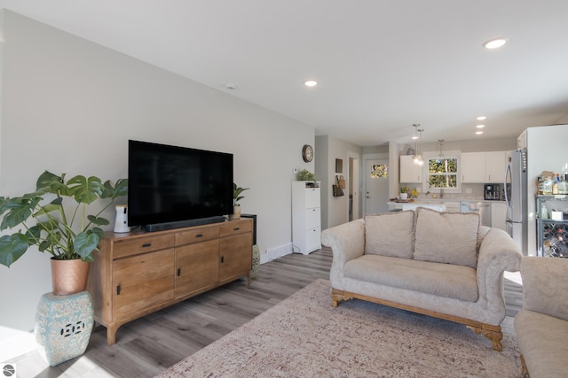 living room with recessed lighting, light wood-style flooring, and baseboards