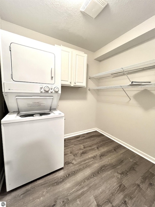 624 S Lake St, Cadillac, MI 49601 - clothes washing area with stacked washing maching and dryer, baseboards, dark wood-style floors, and cabinet space