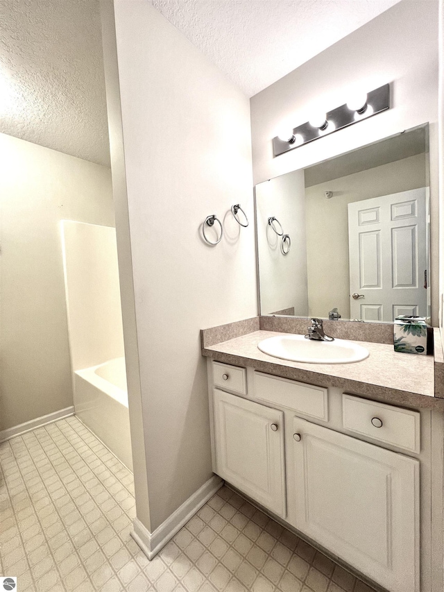 624 S Lake St, Cadillac, MI 49601 - full bathroom featuring vanity, a textured ceiling, and baseboards