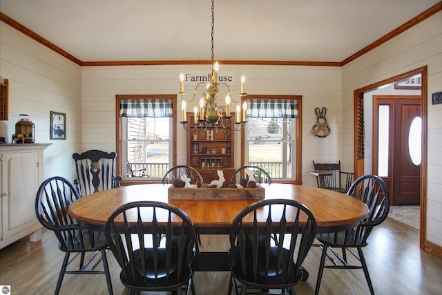 dining area featuring a healthy amount of sunlight, a notable chandelier, ornamental molding, and wood finished floors