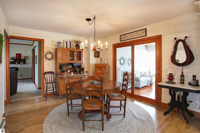 dining space featuring a chandelier, light wood finished floors, and a baseboard heating unit