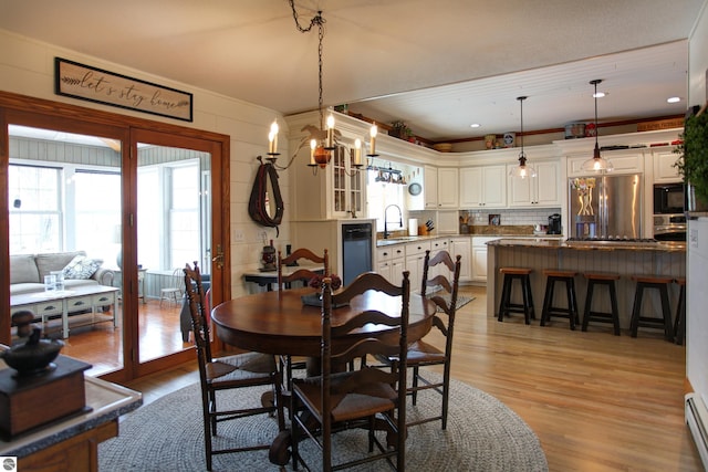 dining room featuring light wood-style flooring, an inviting chandelier, and a baseboard heating unit