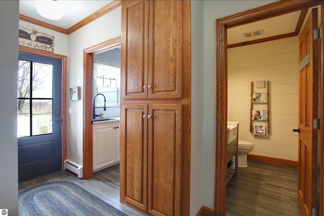 interior space featuring ornamental molding, visible vents, a baseboard heating unit, dark wood-style flooring, and baseboards