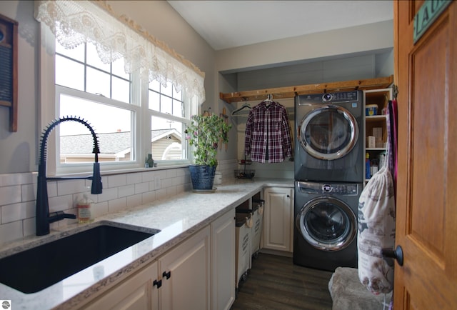 washroom featuring a sink, cabinet space, stacked washing maching and dryer, and dark wood-style flooring