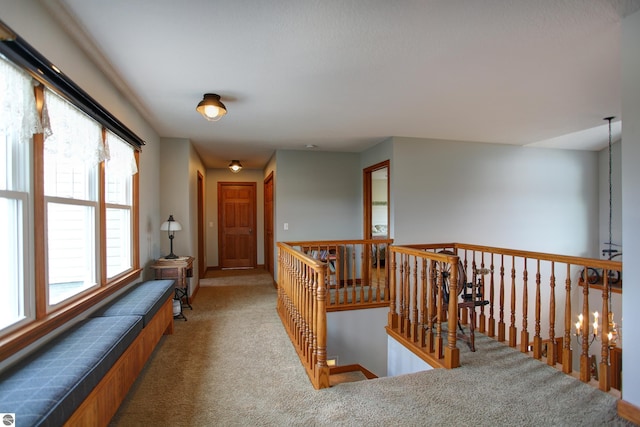 hall featuring an upstairs landing, baseboards, and carpet floors