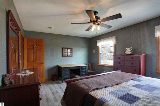 bedroom featuring a ceiling fan, light wood-style flooring, a textured ceiling, and wallpapered walls