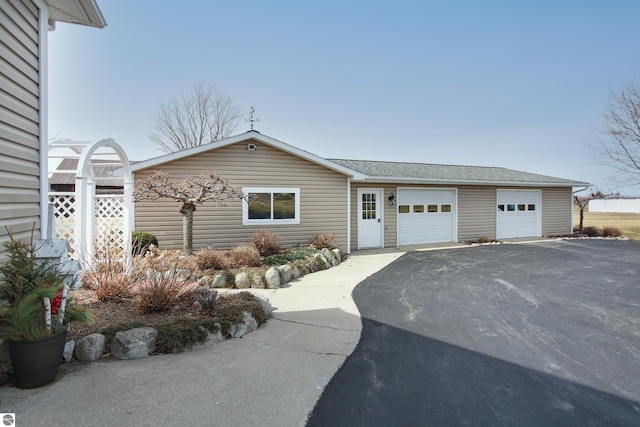 single story home with driveway and a shingled roof