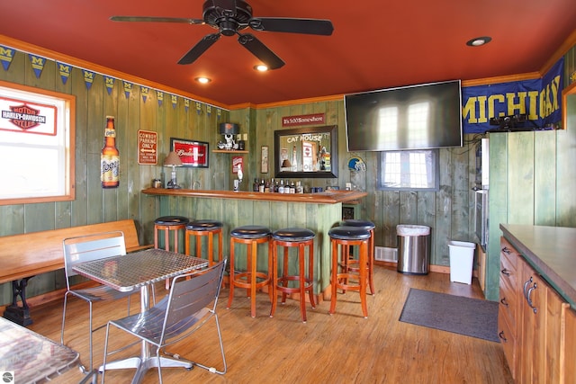 bar featuring ceiling fan, crown molding, a dry bar, and wood finished floors