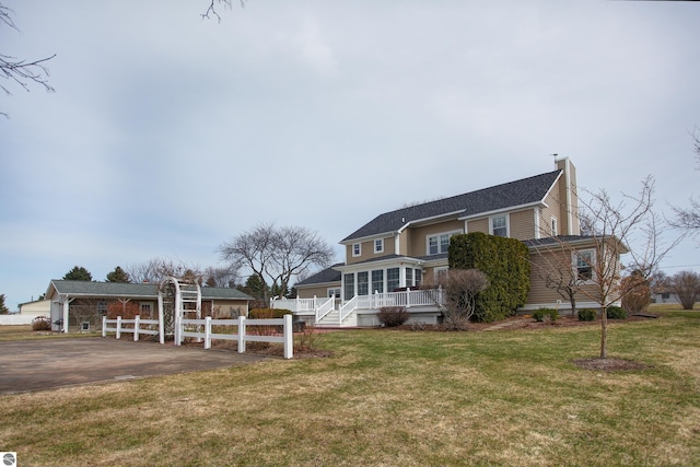 view of front of home featuring a shingled roof, a front lawn, fence, and a chimney