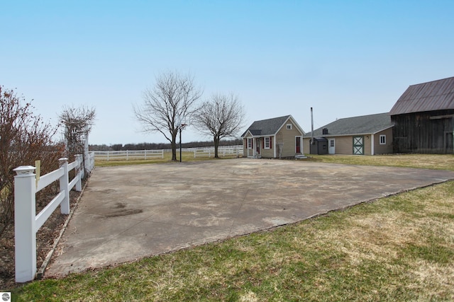view of yard with a barn, driveway, fence, and an outdoor structure