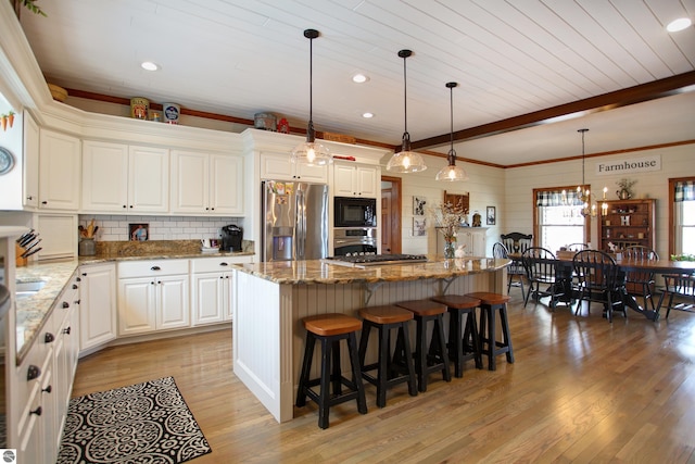 kitchen with light wood-style flooring, a breakfast bar, a center island, stainless steel appliances, and beam ceiling