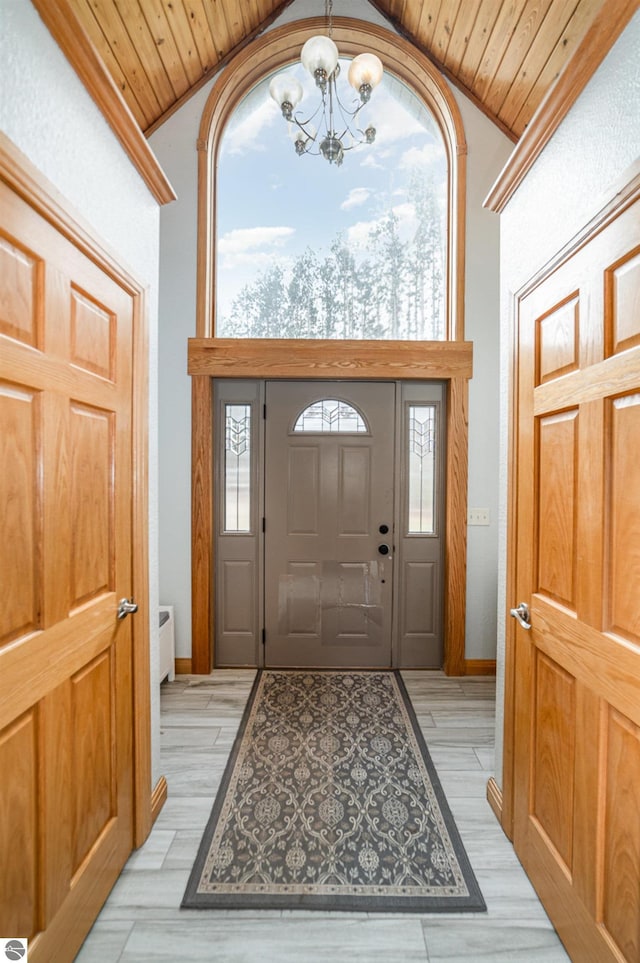 foyer entrance featuring a chandelier, wood ceiling, baseboards, and vaulted ceiling