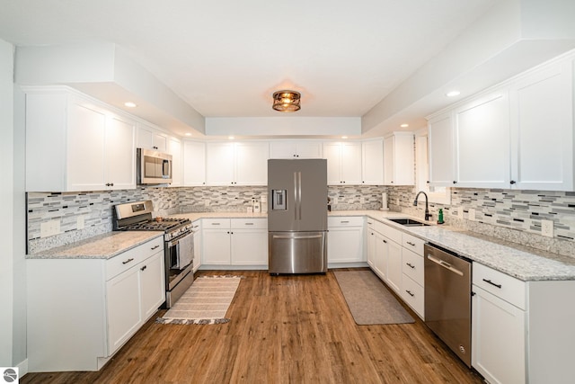 kitchen featuring light wood-style flooring, white cabinetry, appliances with stainless steel finishes, a sink, and backsplash