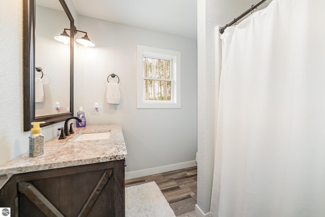 full bathroom with vanity, baseboards, and wood finished floors