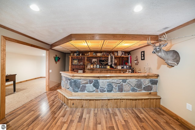 bar featuring baseboards, wet bar, ornamental molding, visible vents, and wood finished floors