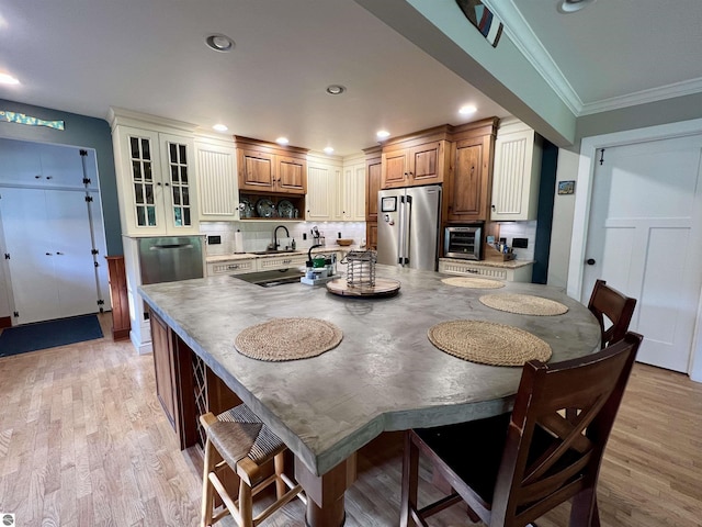 kitchen with light wood-type flooring, recessed lighting, freestanding refrigerator, crown molding, and decorative backsplash