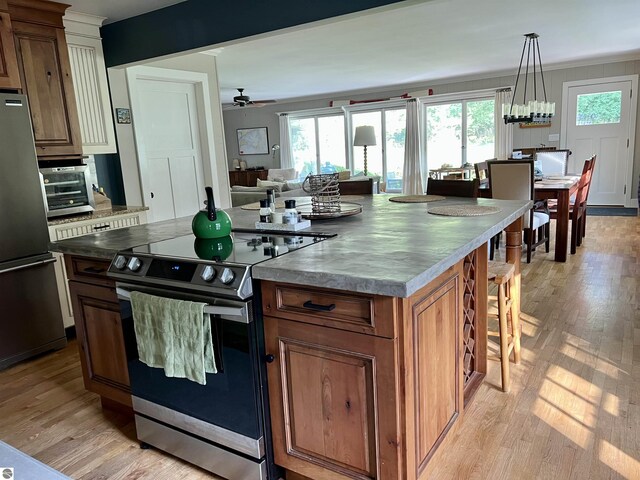 kitchen featuring brown cabinetry, appliances with stainless steel finishes, light wood-style flooring, and a healthy amount of sunlight