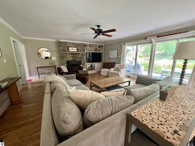 living area featuring a ceiling fan, baseboards, crown molding, and wood finished floors