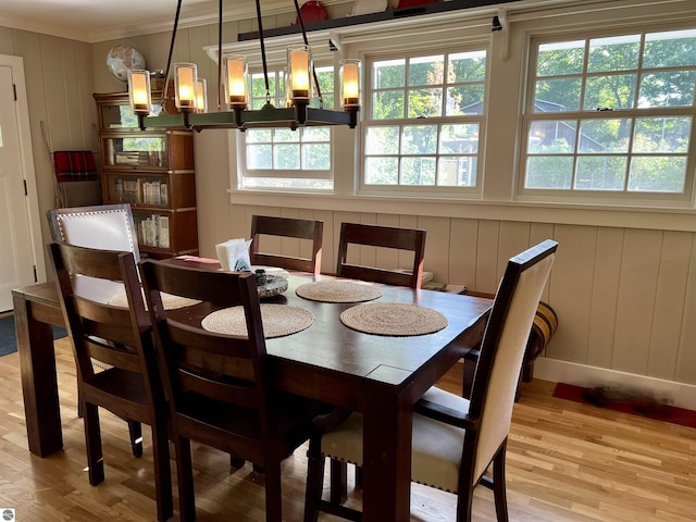 dining area with a decorative wall, light wood-type flooring, and crown molding
