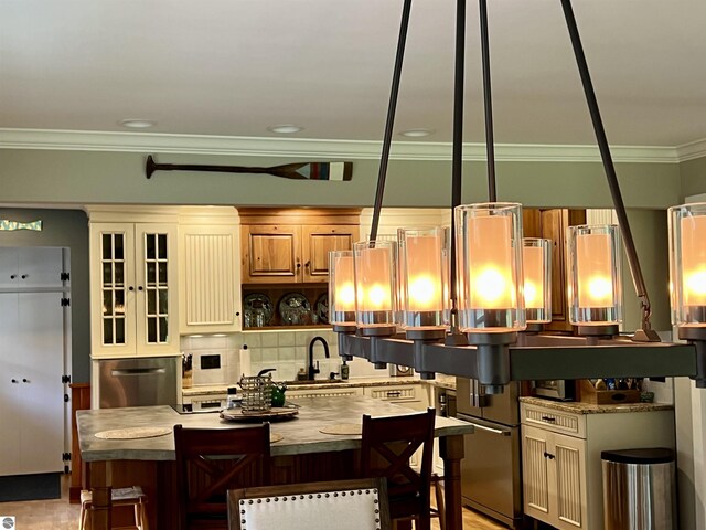kitchen featuring backsplash, a sink, a kitchen island, crown molding, and fridge