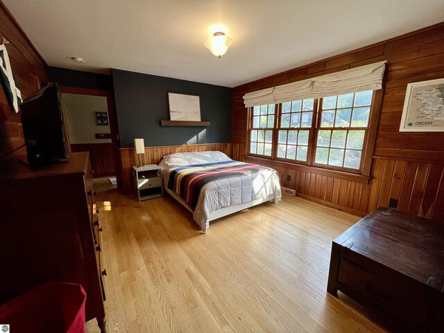 bedroom with wooden walls, a wainscoted wall, and wood finished floors