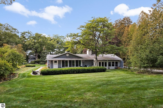 rear view of property featuring a chimney and a lawn