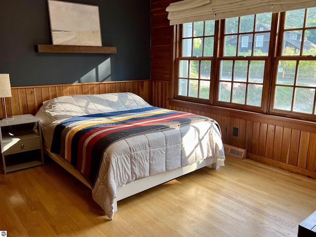 bedroom featuring wooden walls, multiple windows, and visible vents